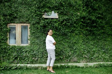 Thai woman smile with green plant wall