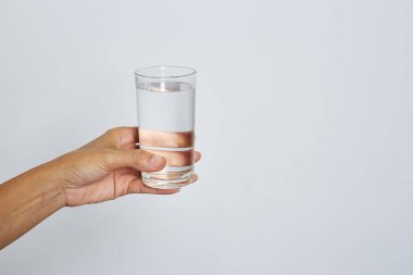 Güzel bir kadın eli, beyaz zemin üzerinde izole edilmiş bir bardak su tutuyor afiş tasarımı için desenli.