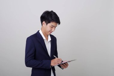 Beyaz arka plan, mimari, mühendislik, inşaat ve ev tasarımı konsepti üzerine not tutan şık takım elbiseli çekici genç işadamı..