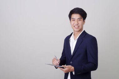 Beyaz arka plan, mimari, mühendislik, inşaat ve ev tasarımı konsepti üzerine not tutan şık takım elbiseli çekici genç işadamı..