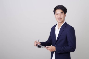 Beyaz arka plan, mimari, mühendislik, inşaat ve ev tasarımı konsepti üzerine not tutan şık takım elbiseli çekici genç işadamı..