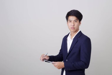 Beyaz arka plan, mimari, mühendislik, inşaat ve ev tasarımı konsepti üzerine not tutan şık takım elbiseli çekici genç işadamı..