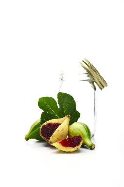 Beyaz arka planda olgun incir ve boş cam şişe, vejetaryen gıda konsepti.