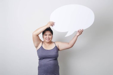 Çekici genç Asyalı tombul kadın konuşma baloncuğunu gri arka planda boş tutarken konuşma balonu sohbeti, yazı için yer, sağlıklı egzersiz konsepti