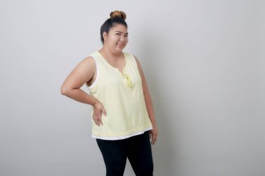 Güzel, tombul, genç Asyalı kadın gülümsüyor. Elleri havada, beyaz arka planda izole edilmiş, afiş tasarımı için desenli bir şey gösteriyor.