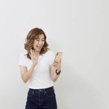 Kadınlar Facetime 'ı gülümseyerek çok mutlu kullanıyorlar. Renkli altın akıllı telefon. Beyaz tişört ve kot pantolon. Metin için boşluk