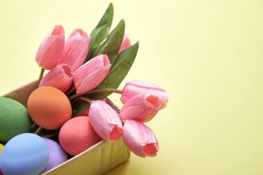 Kutuda pembe laleler ve kağıt sarısı arkaplan üzerinde Paskalya Yumurtası metin için kopyalama alanı