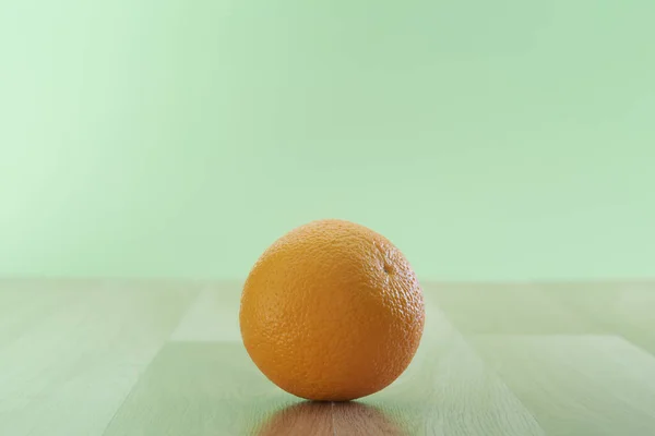 緑の壁の背景に隔離された木製のテーブルの上に新鮮なオレンジの果物 テキストのためのコピースペース — ストック写真
