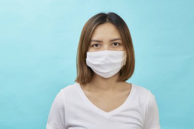 Kahverengi saçlı Asyalı kadın ve koruma amaçlı tıbbi maske açık mavi arka planda tekrar grip. Metnin için alanı kopyala. COVID-19 dövüş konsepti.