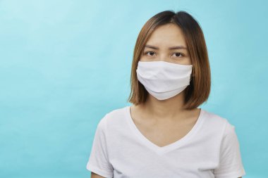 Kahverengi saçlı Asyalı kadın ve koruma amaçlı tıbbi maske açık mavi arka planda tekrar grip. Metnin için alanı kopyala. COVID-19 dövüş konsepti.