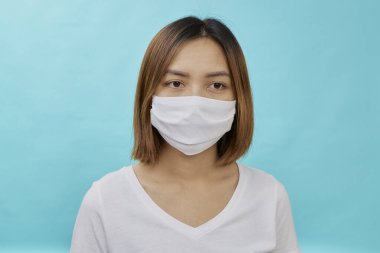 Kahverengi saçlı Asyalı kadın ve koruma amaçlı tıbbi maske açık mavi arka planda tekrar grip. Metnin için alanı kopyala. COVID-19 dövüş konsepti