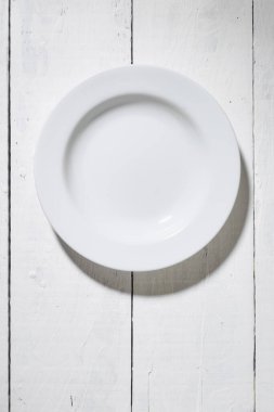 Beyaz tabak ve beyaz tahta masa zemininde fotokopi alanı olan beyaz tabağın üst görüntüsü. metin ve işaretlerle kullanmak için.