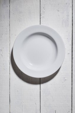 Beyaz tabak ve beyaz tahta masa zemininde fotokopi alanı olan beyaz tabağın üst görüntüsü. metin ve işaretlerle kullanmak için.