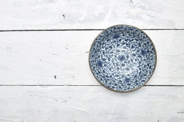 Düz uzanmış, beyaz ahşap masa üzerinde mavi desenli boş porselen tabaka.
