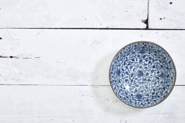 Düz uzanmış, beyaz ahşap masa üzerinde mavi desenli boş porselen tabaka.