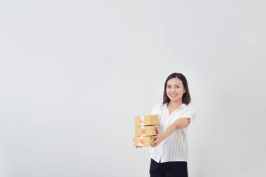 Evde çalışan, gülümseyen genç Taylandlı kadın beyaz arka planda küçük bir paket kutusu, KME işi ve teslimat konsepti tutuyor.