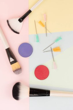 Kozmetik cerrahi vs makyaj, makyaj fırçaları ve şırınga renkli arka planlar üzerinde