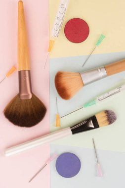 Kozmetik cerrahi vs makyaj, makyaj fırçaları ve şırınga renkli arka planlar üzerinde