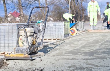 Eldivenlerin ustası katman katman taş döşüyordu. Profesyonel kaldırım işçisi tarafından kaldırım taşı döşenmiş. Kum temeli üzerine gri beton döşeme döşeme