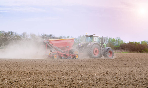 Farmer seeding, sowing crops at field. Sowing is the process of planting seeds in the ground as part of the early spring time agricultural activities. 