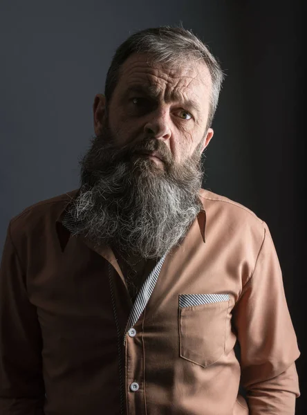 Foto de un viejo gruñón enojado que parece muy disgustado. Hombre con barba larga en la cara. Cara de cerca mirando a la cámara . — Foto de Stock