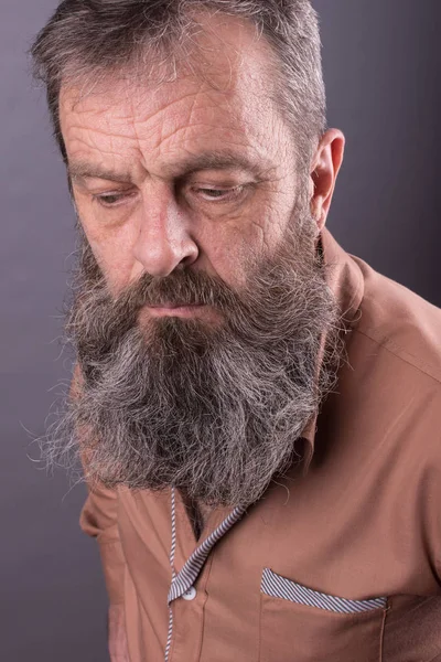 Foto de un viejo gruñón enojado que parece muy disgustado. Hombre con barba larga en la cara. Cara de cerca mirando a la cámara . — Foto de Stock