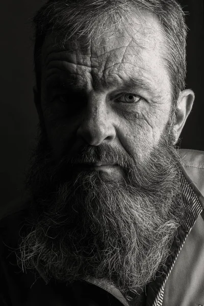 Portret alb-negru al unui bătrân cu barbă plină. Închide capul împușcat cu aproape de față. Expresie facială gravă morocănoasă . — Fotografie, imagine de stoc