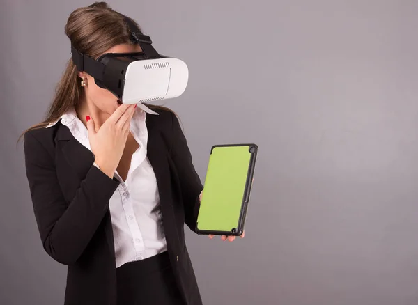 Geschäftsfrau mit tragbarer Technologie und Brille. selbstbewusste junge Frau im Business-Anzug in Virtual-Reality-Headset mit Schnittstelle selektiver Fokus Hände auf einem Tablet leeren grünen Bildschirm. — Stockfoto