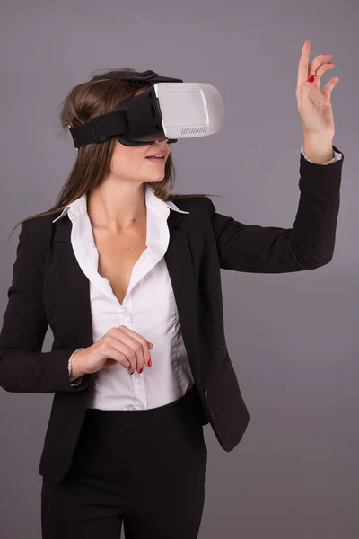 Business Woman in wearable technology VR glasses. Confident young woman in a business suit in virtual reality headset  with Interface selective focus hands pointing in the air
