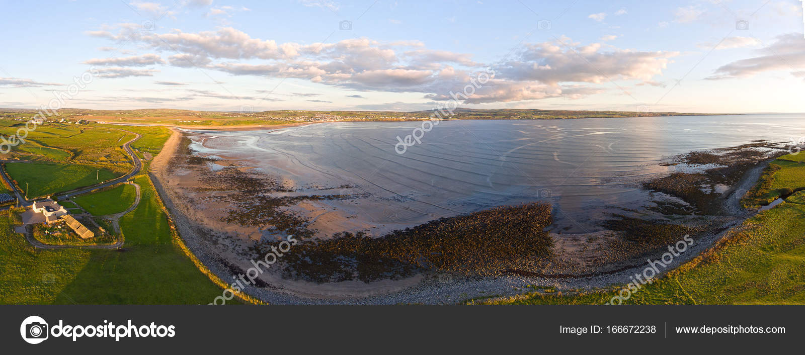 Aerea Birds Eye View di un paesaggio di campagna irlandese di tramonto In County Clare Irlanda Lahinch Beach in lontananza lungo la strada atlantica
