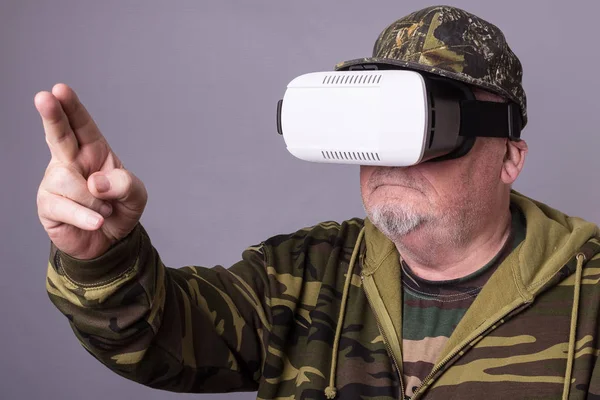 Senior Mann in tragbarer Technologie vr Brille. selbstbewusster alter Mann in Tarnkleidung in Virtual-Reality-Headset mit selektivem Fokus in der Luft — Stockfoto