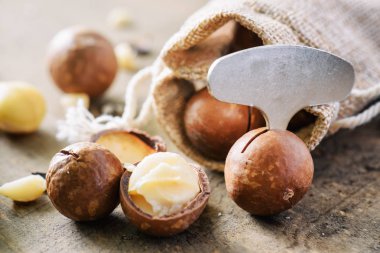 Ahşap tahta üzerinde metal açacağı ile Macadamia fındık