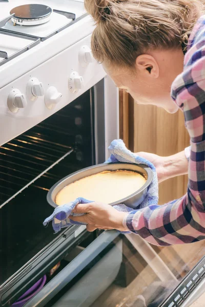 Chica usando paño de cocina para sacar pastel de queso del horno — Foto de Stock