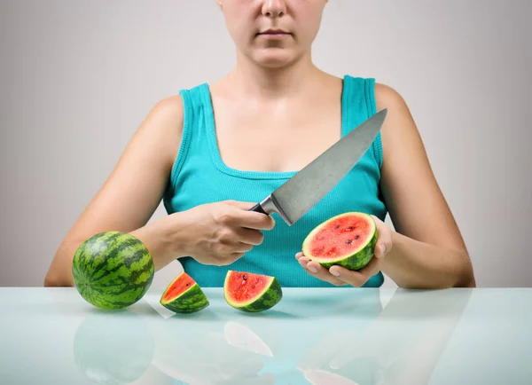 Girl using big knife for cutting ripe red small watermelons — Stock Photo, Image