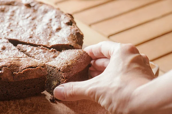 Hand taking piece of delicious freshly baked brownie cake — Stock Photo, Image