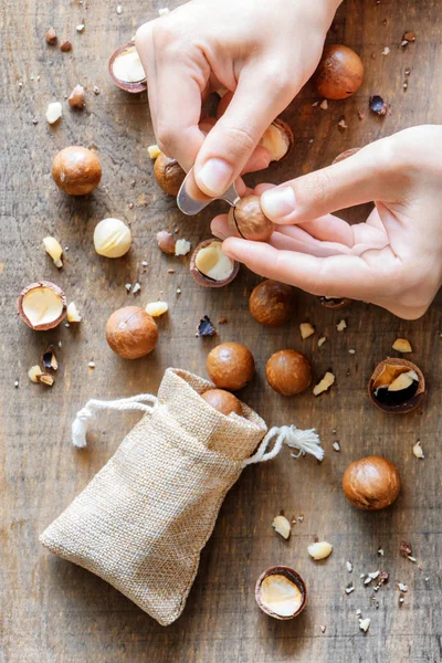 Top view of hands opening Macadamia nut with opener — Stock Photo, Image