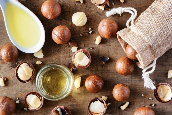 Macadamia nuts and natural macadamia oil on wooden board — Stock Photo, Image