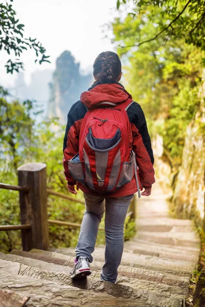 Fiatal női turista a piros hátizsák, csökkenő a lépcsőn — Stock Fotó