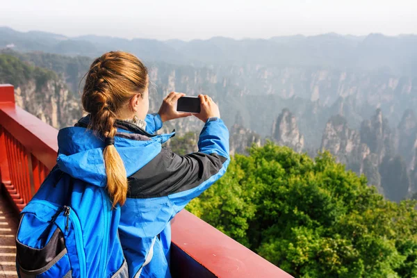 Female tourist with smartphone taking photo of mountains — Stock Photo, Image