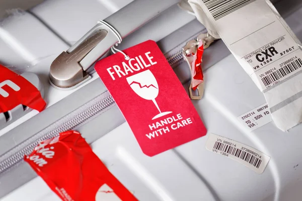 Red luggage tag (Fragile) attached to suitcase at airport — Stock Photo, Image