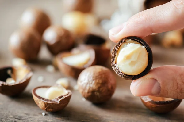 Vue rapprochée des doigts tenant la noix de Macadamia. Aliments sains — Photo