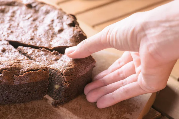 Vista de perto da mão tomando parte de brownie recém-assado — Fotografia de Stock