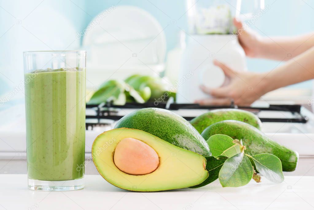 Fresh avocado smoothie and ripe green avocados on kitchen table