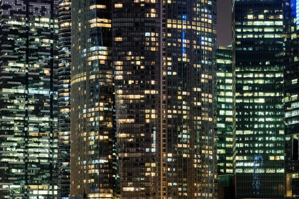 夜の高層ビルの光る窓。夜の街並み — ストック写真