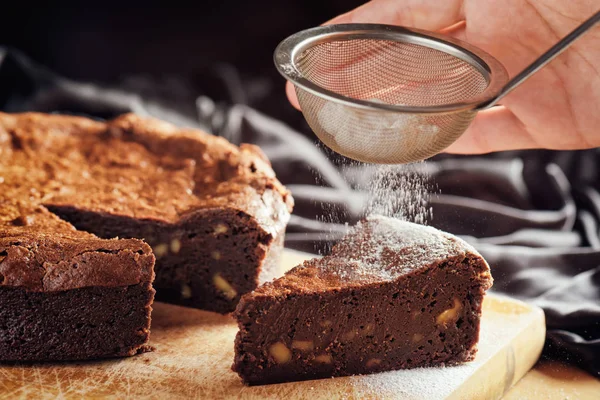 Hands holding sieve with powdered sugar and sprinkling cake — Stock Photo, Image