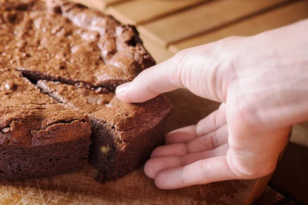 Nahaufnahme von Hand nehmen Stück Schokolade Brownie Kuchen — Stockfoto