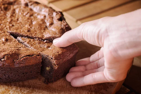 Vista de cerca de la mano tomando pedazo de pastel de chocolate brownie — Foto de Stock