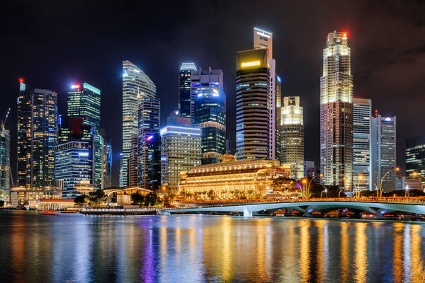 Amazing night view of skyscrapers by Marina Bay at downtown of Singapore. Colorful city lights reflected in water of the bay. Beautiful cityscape. Singapore is a popular tourist destination of Asia.