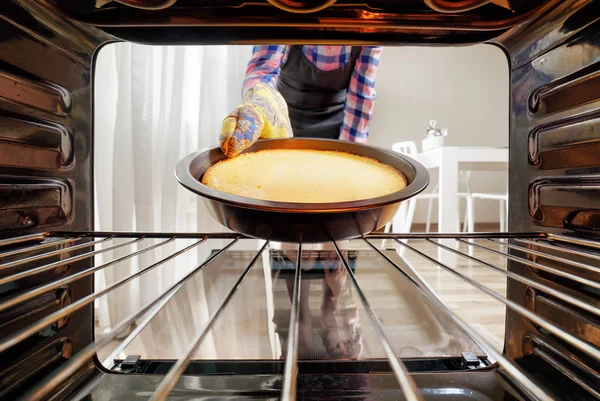 Dona de casa tomando cheesecake fora do forno na cozinha — Fotografia de Stock