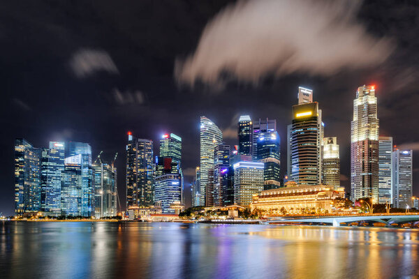 Fantastic night view of skyscrapers by Marina Bay at downtown of Singapore. Colorful city lights reflected in water of the bay. Amazing cityscape. Singapore is a popular tourist destination of Asia.
